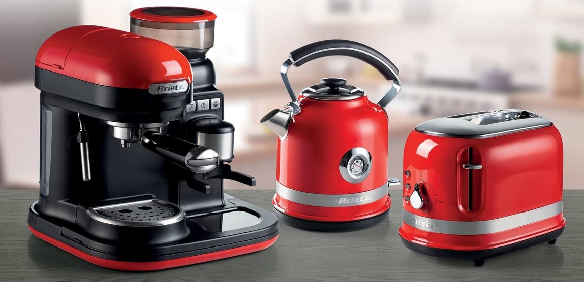 Кухненски уреди Red ariete, включително машина за еспресо, чайник и тостер, подредени върху дървен плот.