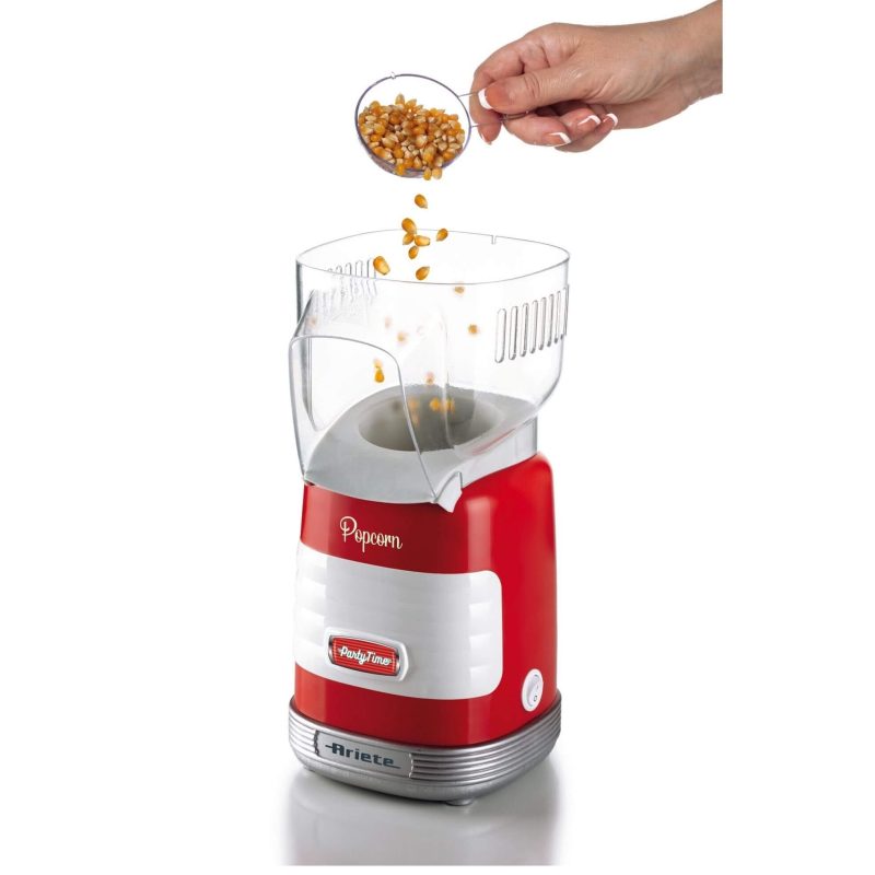 Ръка, изсипваща зърна пуканки в червено-бяла електрическа машина за пуканки.