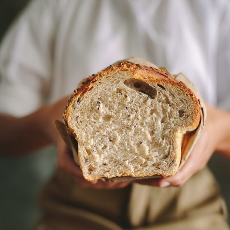 Човек, който държи прясно нарязан хляб от Хлебопекарна PANEXPRESS 1000, показващ текстурата на трохите на хляба.