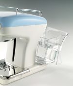 Модерна еспресо машина с прикрепен прозрачен стъклен резервоар за вода, поставена на светлосив фон.