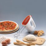 MIXY ORANGE левитира с отделени бъркалки, заобиколен от съставки и предмети, свързани с печенето и приготвянето на пица, включително брашно, яйца, топка тесто, оранжева дървена дъска, сладкиши.