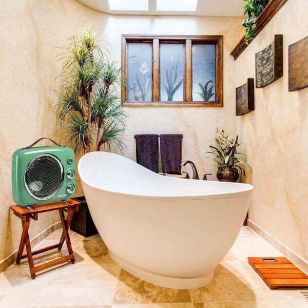 Елегантна баня със свободностояща бяла вана, декоративни растения, ретро зелено радио на табуретка и стенни картини.