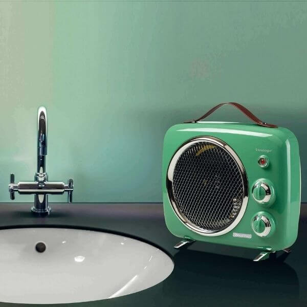 Зелено радио в ретро стил с кожена дръжка стои на плот до модерна бяла мивка и сребърен кран, срещу стена в синьо-зелен цвят.