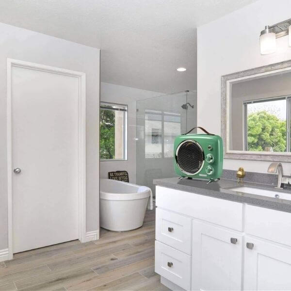 Модерна баня с бели шкафове, стъклен душ, тоалетна и винтидж зелен вентилатор на плота.