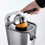 Човек използва ръчна Цитрус преса PRO JUICE, за да изстиска сок от портокал.