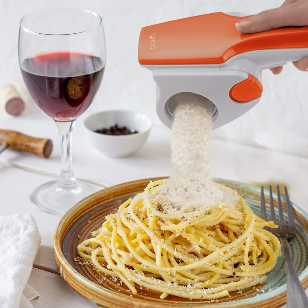 Човек използва Електрическо ренде GRATÌ 2.0, за да поръси паста в чиния.