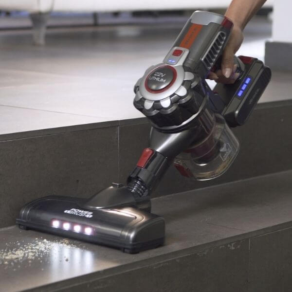 A person is using a Вертикална безжична прахосмукачка SCOPA 22V handheld cordless vacuum cleaner to pick up debris from a kitchen counter.
