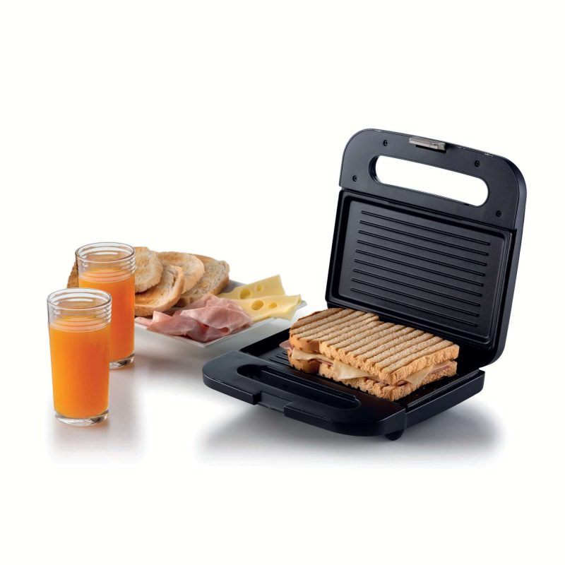 Сандвич мейкър тостер ЗАКУСКА с филия хляб и чаша портокалов сок.