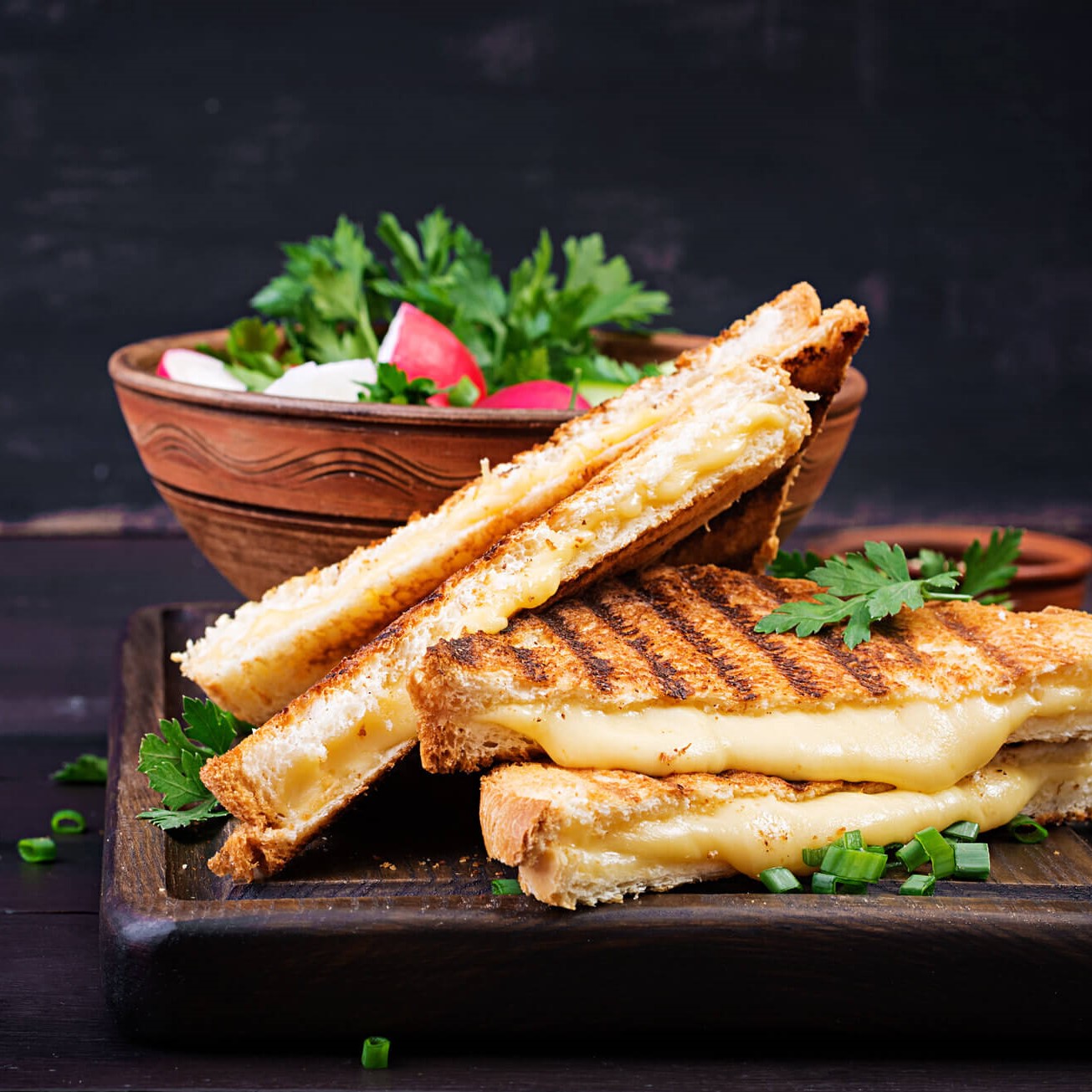 Тостер ЗАКУСКА Сандвич със сирене на скара с репички и салата върху дървена чиния.
