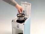 Човек поставя филтърната кошница Ariete с утайка от кафе в отворена кафемашина.