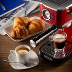 Кафемашина ESPRESSO SLIM MODERNA с 2 чаши кафе, кроасани и вестник на дървена маса.