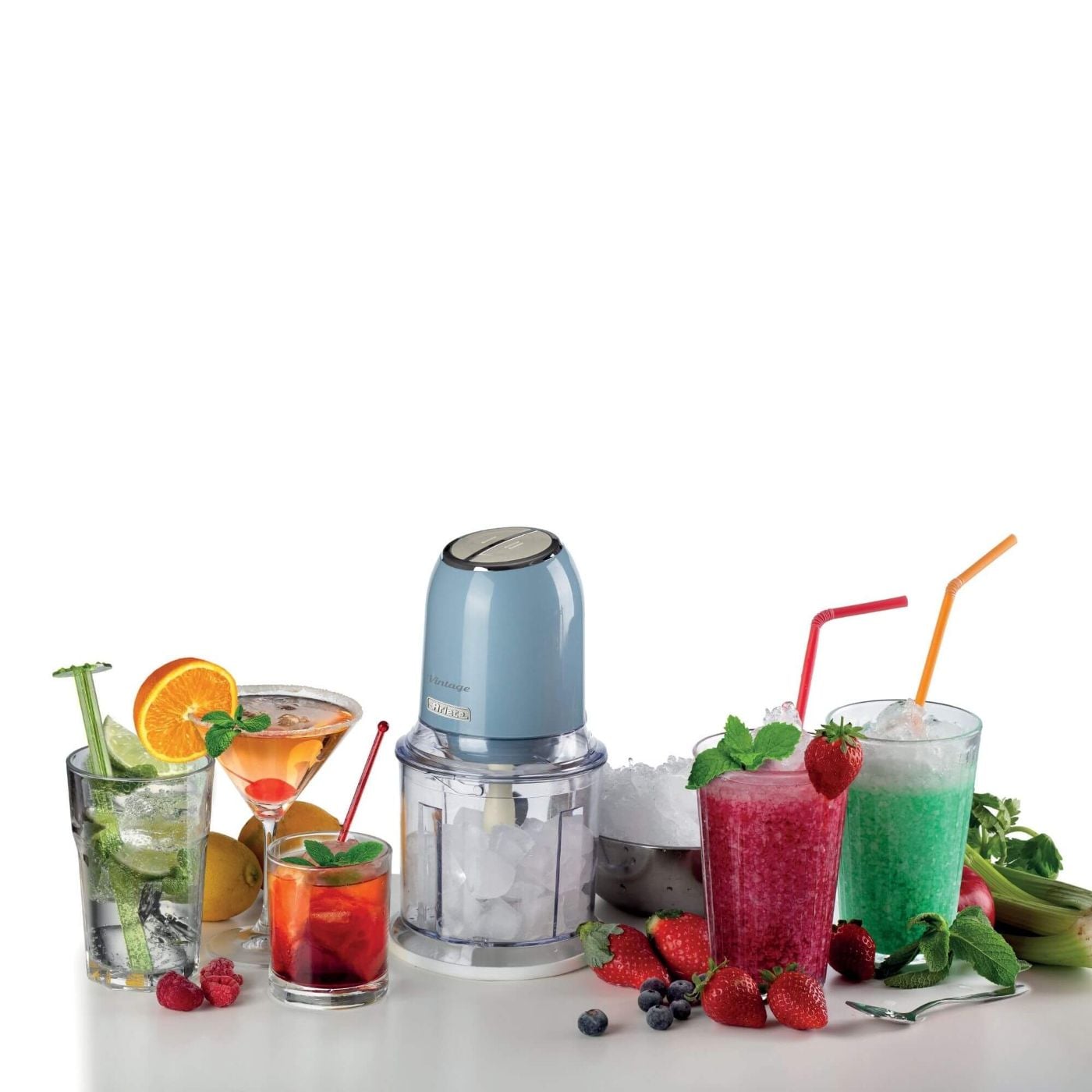Блендер Ariete сред живи напитки, лед, горски плодове, мента и цитрусови плодове върху девствено бяла маса.