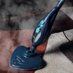 Парочистачка STEAM MOP 10 в 1 син цвят почиства килим с бежови, кафяви и червени части с пара.