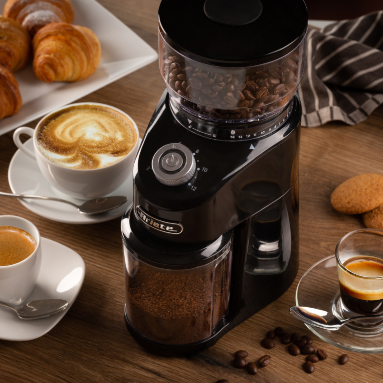 Електрическа кафемелачка COFFEE GRINDER върху дървена маса с кафе, кроасани и сладкиши.