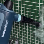 Парен пистолет VAPORÌ JET разпръсква пара, за да почисти стена със зелени плочки.