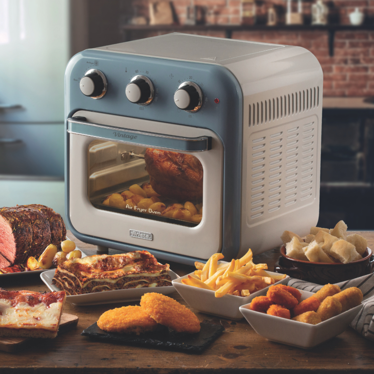 Фурна с горещ въздух и грил Vintage AIR FRYER 16 л. на кухненския плот с приготвени ястия: пържени картофи, пиле и хляб.