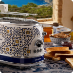 Тостер VINTAGE, за 2 филии – Capri в синьо и жълто на масата с препечен хляб, зърнени храни, мед и конфитюр на открито.