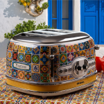 Тостер VINTAGE, за 4 филии – модел „Positano“ с мозаечен десен, стои върху подходяща покривка до синьо прозорче.