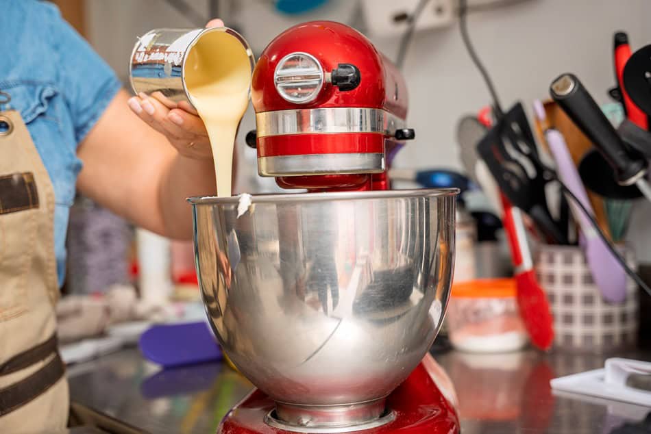 pastry chef pouring condensed milk into stand mixe 2025 03 20 17 00 10 utc