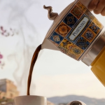 Електрическата кафемашина „Moka Vintage Positano“ налива ароматно кафе в чаша, от която се издига пара, на фона на нежна музика.