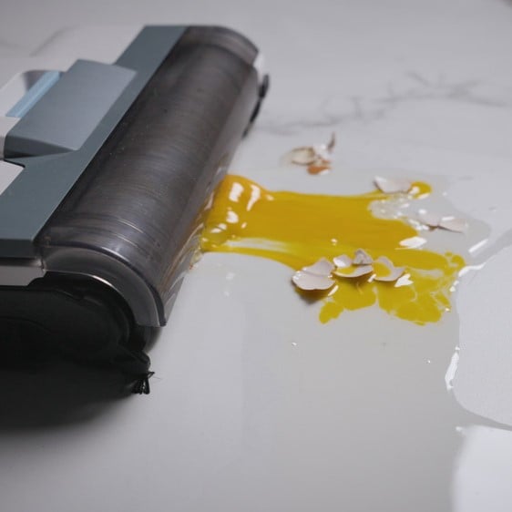 Вертикална прахосмукачка Aqua Force Wash & Vacuum почиства яйце и черупки от бял под.