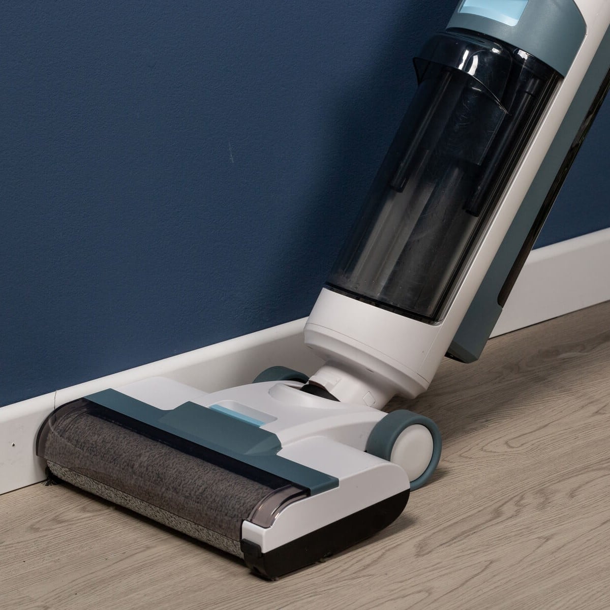 Вертикална прахосмукачка Aqua Force Wash & Vacuum почиства до синя стена и светъл дървен под.