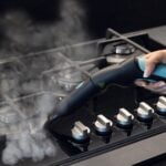 С помощта на парочистачката X-Vapor Comfort, 5 бара, човек почиства копчетата и повърхността на газовата печка.