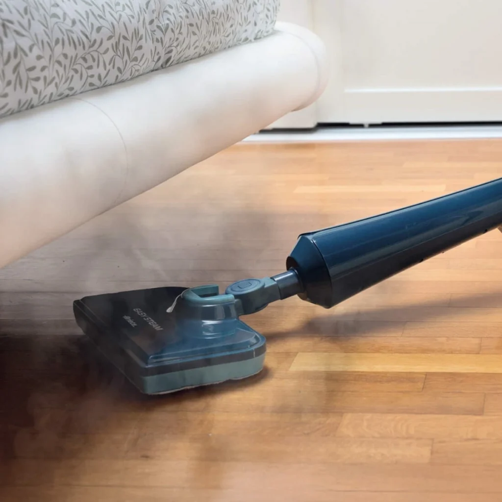 Парочистачка Easy Steam почиства дървен под под бял диван, с пара излизаща от главата на мопа.