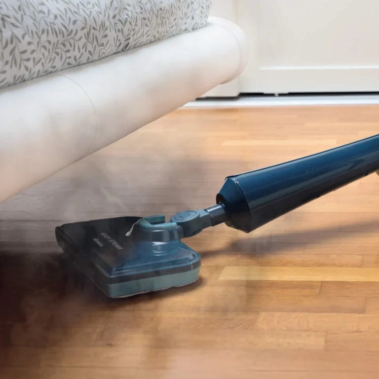 Парочистачка Easy Steam почиства дървен под под бял диван, с пара излизаща от главата на мопа.