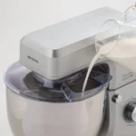 Някой налива мляко в Планетарен миксер Gourmet Supreme 10L с прозрачна купа и сребърен капак.