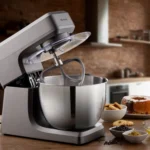 Планетарен миксер Gourmet Supreme 10L с метална купа стои на плота до изпечени изделия и съставки.