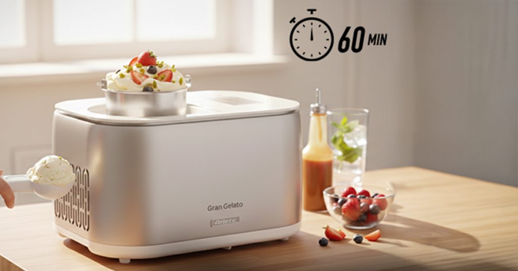 Машина за сладолед „A Gran Gelato 4 в 1“ с компресор в сребрист цвят стои върху дървена маса и приготвя сладолед, а до нея са подредени плодове и гарнитури. На заден план се вижда икона с таймер за 60 минути.